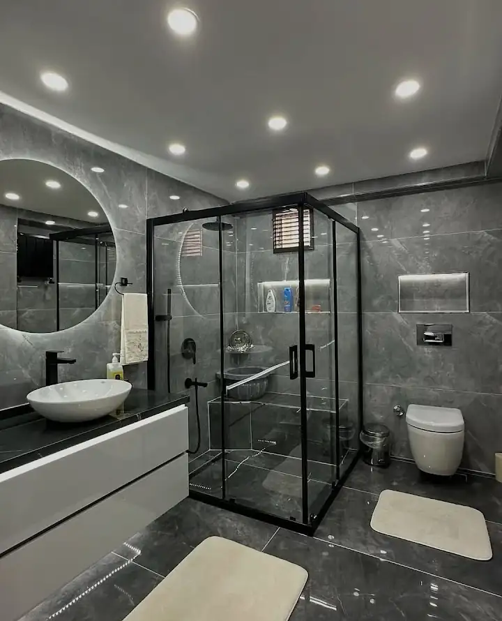 Gri mermer görünümlü, cam duşakabinli banyo